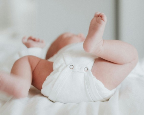 Baby laying on a bed.