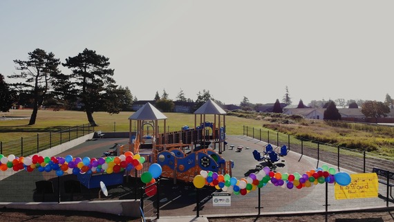 Aerial view of a fenced playground. On the fence are colorful party balloons.