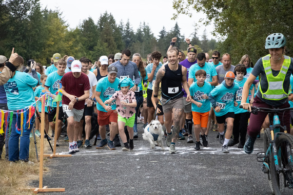 Racers of all ages take off from a finish line.