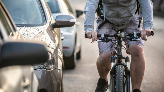 Person on bicycle rides next to cars on the roadway