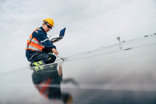 Solar worker checks panels with laptop computer.