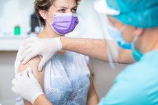 Woman wearing a purple mask and getting a flu shot (iStock)