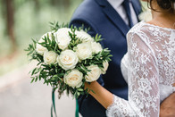 bouquet of white roses with a cropped bride and groom