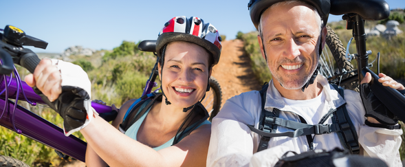 Man and woman carrying mountain bikes with a desert background
