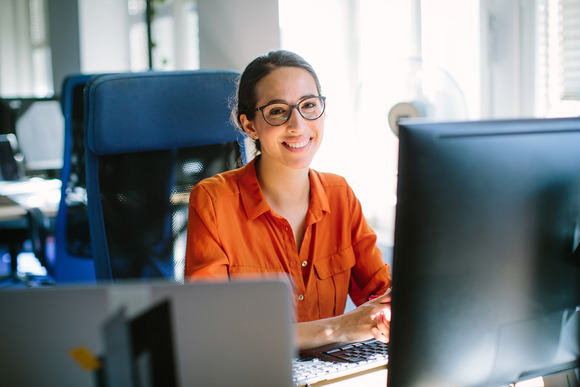 Woman employee smiles and works on her computer.