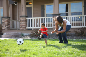 mom and son playing soccer in yard