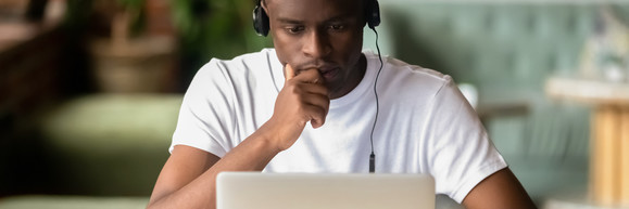 Adult on laptop wearing headphones