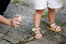 spraying bug spray on child