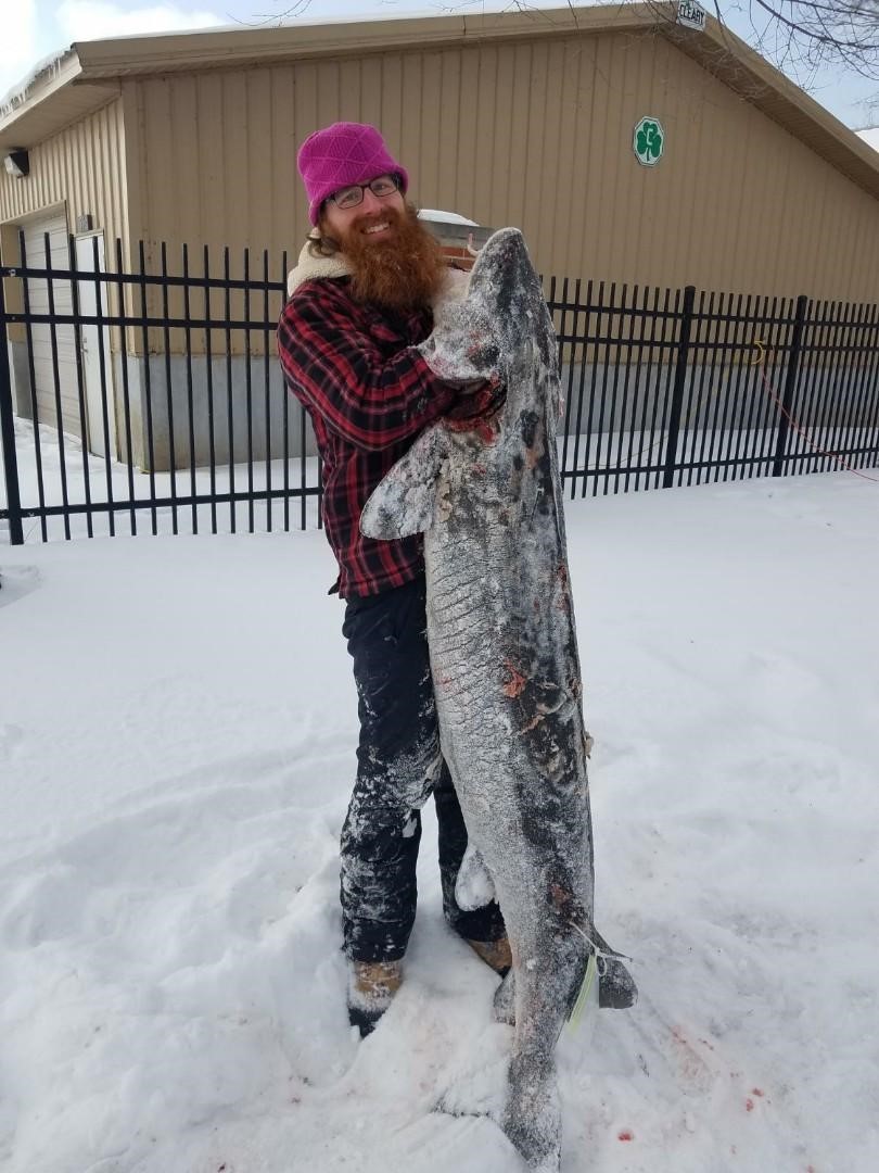 Spearer Owen Tesson poses holding his snow-covered 130.2 pound (73.1 inches) F2 female on day 7 of the 2021 sturgeon spearing season. 