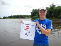 volunteer holding towel with invasive species information on it, water in the background