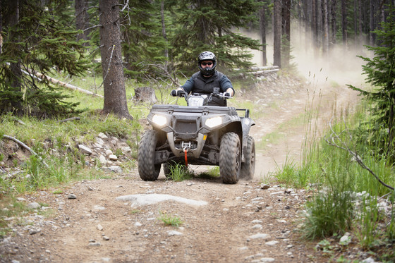 An image of a person riding an ATV on a dirt road. 