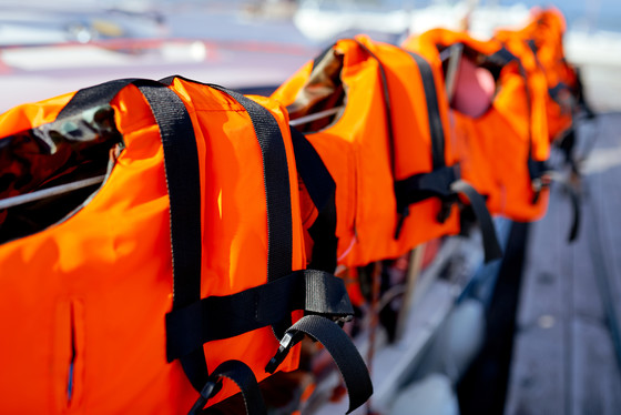 life jackets lined up on rail of boat