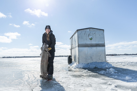 A woman holding up a large sturgeon.