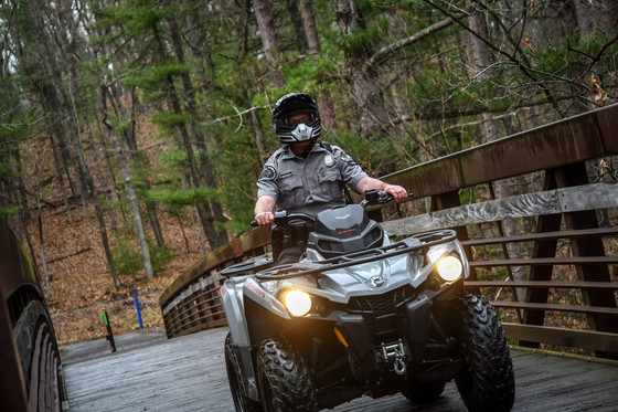 DNR warden wearing helmet riding ATV