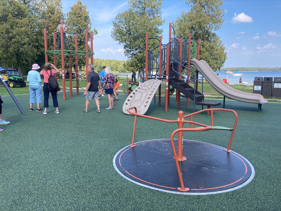 A group of people enjoying the new accessible playground at the park.