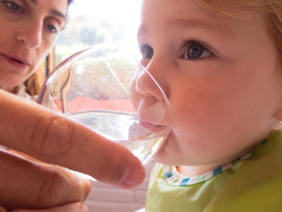 Baby drinking water from mother's hand