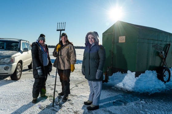 women holding spears to spear sturgeon on an iced-over lake