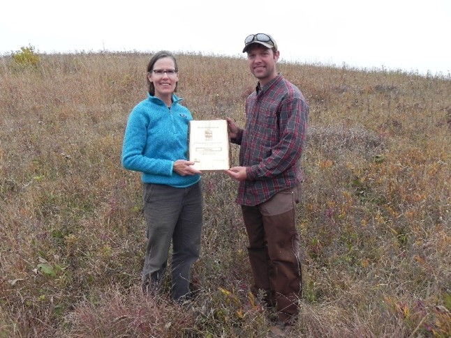 Heidi Hankley and Jared Urban pose for a photo with Hankley?s State Natural Areas Steward of the Year Award at York Prairie State Natural Area.