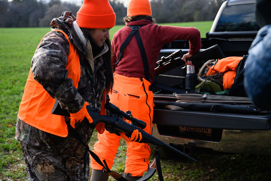 woman wearing blaze orange safely handling a rifle