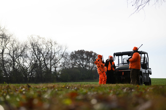 group of hunters wearing blaze orange standing around ATV