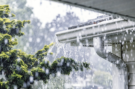 A heavy rain overflowing the gutters on a house.