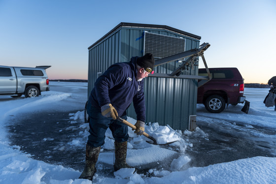 man shovels out area around his sturgeon spearing shack