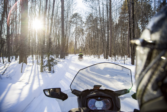 friends snowmobile through the north woods of saint germain