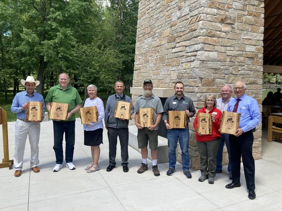 Nine 2021 Invader Crusader Award Winners pose with their awards.