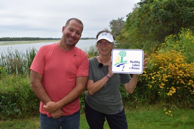 Patrick Kilbey and Karyn Niin Kitigade standing in front of Karyn?s native shoreland planting. 