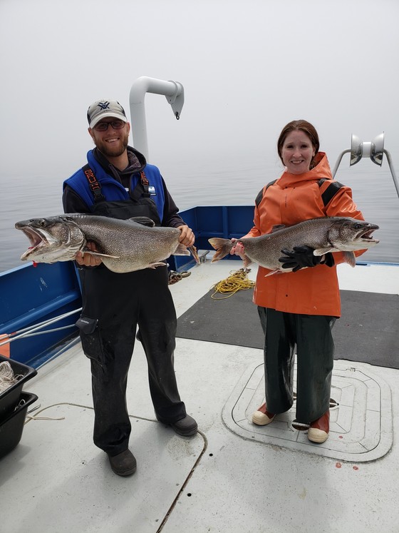 two people holding lake trout