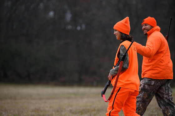 A man mentors a woman on hunting deer.