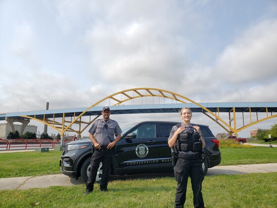 two wardens standing in front of a warden vehicle