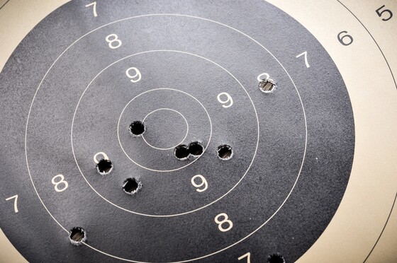 A closeup of a black and tan shooting range target with several bullet holes in the middle.