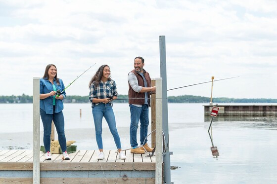 a younger girl fishing on a pier with her parents