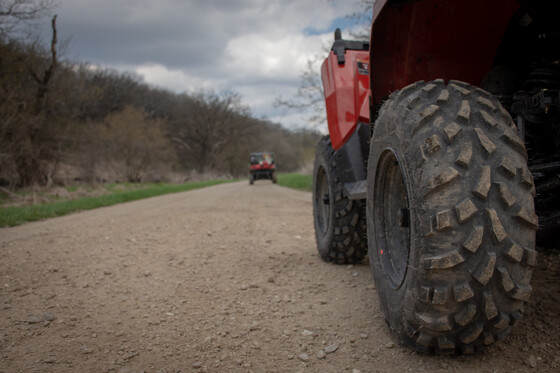 close up of red atv wheel with another atv down the road