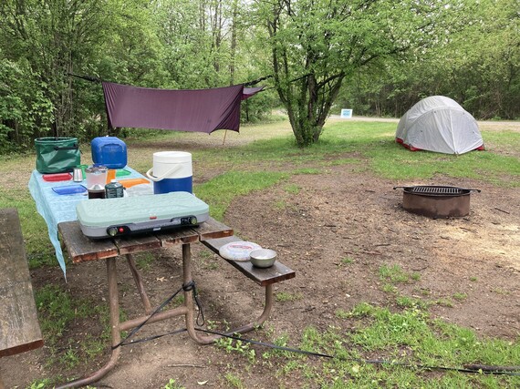 Campsite with tent and hammock and picnic table of kitchenware