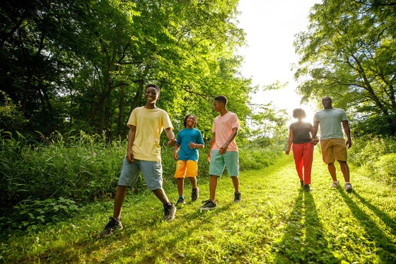 a family walking through a green trail with trees around them