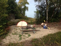 Tent and picnic table with camping supplies showing kayaker campsite