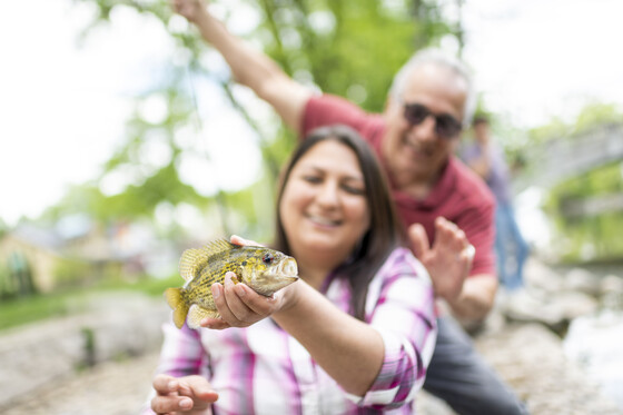 Two people smiling holding a fish