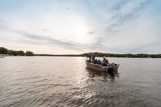 three friends fishing on a boat on a lake