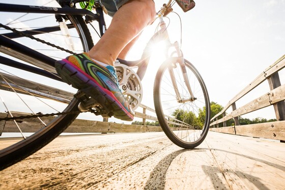 A close up of a biker's pedal. The bike is on a pier on a sunny summer day.