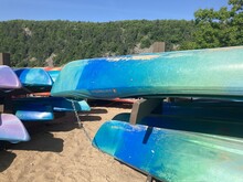 Kayaks on racks against a backdrop of lake and wooded bluffs