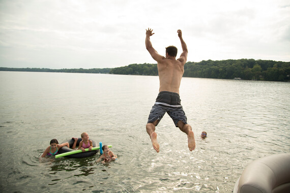 Man jumping into lake from pontoon