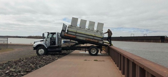 fish being pumped into a lake from a holding tank on board a truck