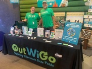 Two people standing in front of a display table with state park information