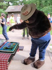 Smokey Bear blows out candles on a birthday cake