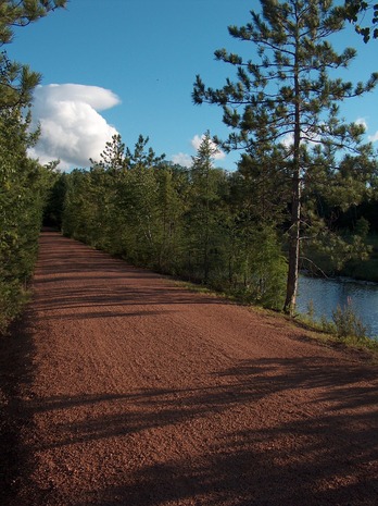 Gravel trail, river and northwoods forest.