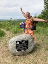 Woman standing by rock with a plaque for the start of the Ice Age Trail
