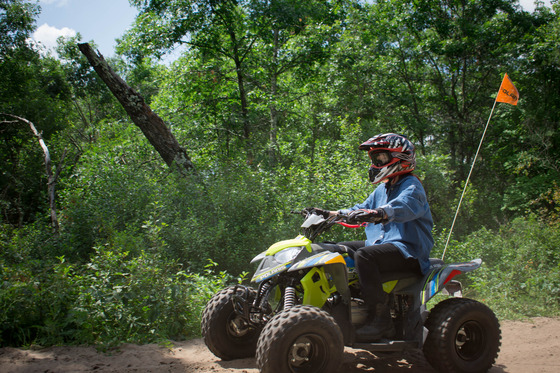 A teenage girl rides on an ATV wearing her helmet.