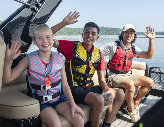 one adult and two children wearing life jackets aboard a boat